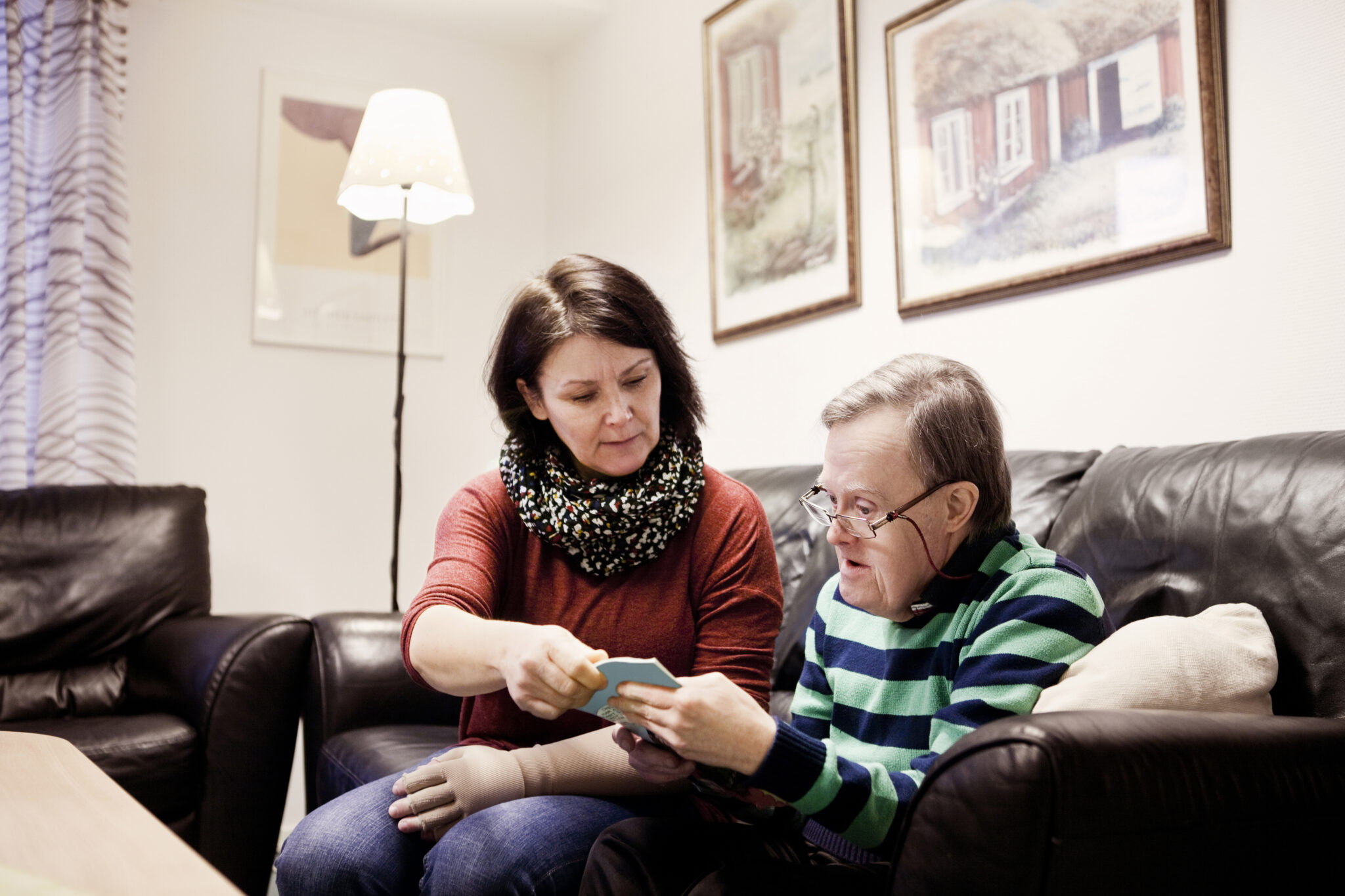 Healthcare worker assisting senior man with down syndrome in reading book